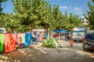 a group of tents in a parking lot with trees at Càmping Bellsol in Pineda de Mar
