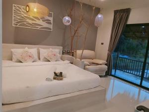 a bedroom with a white bed and a living room at Suwi Coco Ville Resort in Ubon Ratchathani