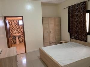 a bedroom with a bed and a door to a bathroom at Belle Villa Nassima in Thiès