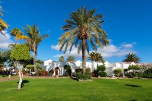 a white building with palm trees in a park at Sol Barbacan in Playa del Ingles
