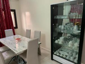 a dining room with a table and a glass display case at Belle Villa Nassima in Thiès