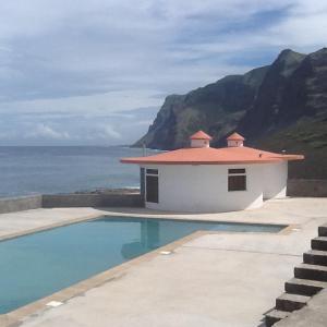 a building with a swimming pool next to the ocean at Questel BronQ in Chã da Igreja