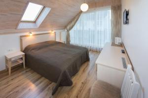 a bedroom with a bed and a desk and a window at Vila Domino in Palanga