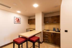 a kitchen with a table and two red stools at Ramada Hotel & Suites by Wyndham Yerevan in Yerevan