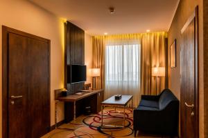 a hotel room with a television and a chair and a desk at Ramada Hotel & Suites by Wyndham Yerevan in Yerevan