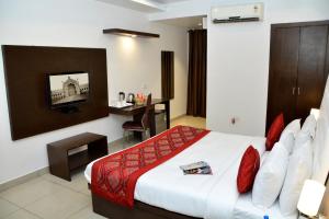 ein Hotelzimmer mit einem großen Bett und einem Schreibtisch in der Unterkunft Hotel Surya International in Lucknow