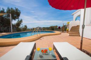 a swimming pool with a table and an umbrella at Casa Infinidad in Moraira