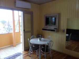 a dining room with a table and chairs and a television at Pousada Campanário in Cambara do Sul