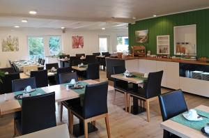 uma sala de jantar com mesas e cadeiras e paredes verdes em Hotel Dat greune Eck em Soltau