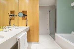 Un baño con lavabo, espejo y bañera. en Eurostars Palacio de Cristal, en Oviedo