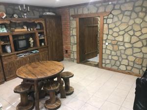 a room with a table and stools and a stone wall at Садиба Червона калина Private estate Chervona Kalyna in Yaremche
