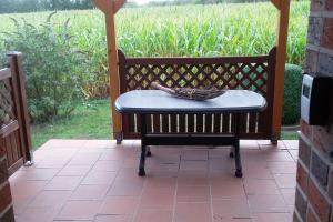 a bench sitting on a porch in front of a field of corn at Gästewohnung von Oesen in Osterholz-Scharmbeck