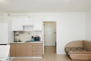 ペルミにあるAbri Luxeの白いキャビネットとソファ付きのキッチンが備わります。