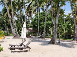 eine Hängematte, ein Stuhl und ein Sonnenschirm am Strand in der Unterkunft Flat Club Meridional in Tamandaré