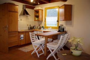 cocina con mesa de madera y sillas blancas en Gut Müllerleile en Gengenbach