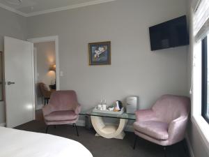 a room with two chairs and a desk and a tv at Stay Taupo in Taupo