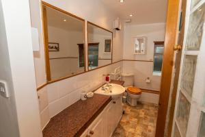 uma casa de banho com um lavatório, um WC e um espelho. em Eithin Bach em Caernarfon