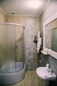 La salle de bains est pourvue d'une douche en verre et d'un lavabo. dans l'établissement Котедж "Солард", à Yaremtche