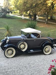an old black car parked on a gravel road at Manoir de la Marjolaine in Cabourg