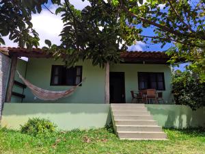 une maison verte avec un hamac en face de celle-ci dans l'établissement Village do Capão, à Vale do Capão