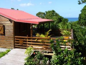 Cabaña con techo rojo y porche con plantas en Kaz Luciole en Deshaies