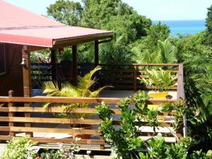 a wooden deck with a gazebo and some plants at Kaz Luciole in Deshaies