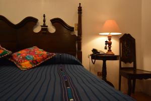 a bedroom with a bed with a lamp and a phone at Hotel Candelaria Antigua in Antigua Guatemala