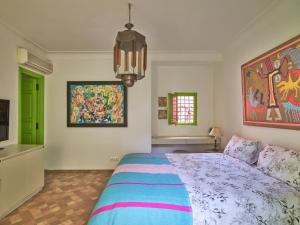 1 dormitorio con 1 cama y una pintura en la pared en Riad Volubilis en Marrakech