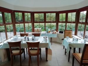a dining room with tables and chairs and windows at Álaind Lodges, Sneem in Sneem