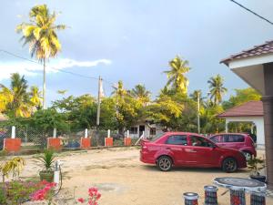 two cars parked in a parking lot with palm trees at Desa Besut Inn in Kuala Besut