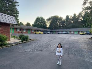 Baw Beese Inn في Hillsdale: فتاة صغيرة تقف في وسط موقف للسيارات