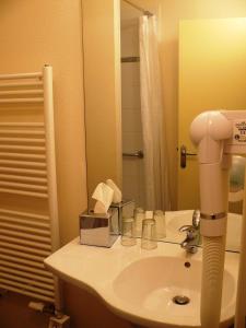 y baño con lavabo y espejo. en Le Parc Des Fees Hôtel Retaurant & Spa, en La Bourboule