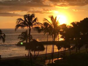 a sunset over a beach with palm trees and the ocean at Beach Villa at Ko'Olina in Kapolei