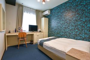 a bedroom with a bed and a desk with a computer at New Osaka Hotel Shinsaibashi in Osaka