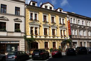 un edificio amarillo con coches estacionados frente a él en Hotel Roudna en Plzeň