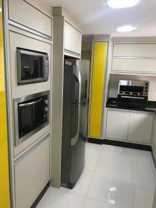 La cuisine est équipée d'un réfrigérateur en acier inoxydable et d'un four micro-ondes. dans l'établissement MARAVILHOSO apartamento QUADRA MAR em BC, à Balneário Camboriú