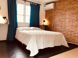 a bedroom with a white bed with a brick wall at Alondra Boutique in Villa Cura Brochero +73 photos