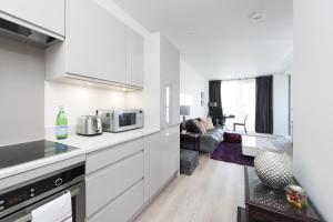 ロンドンにあるModern 1 Bedroom Flat near Canary Wharf in Londonの白いキャビネット付きのキッチン、リビングルーム