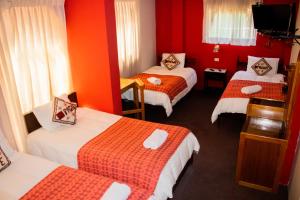 Habitación de hotel con 3 camas y paredes rojas en Pacha Suite, en Puno