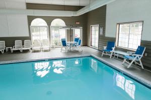 a swimming pool with blue chairs and a table at Breakers Resort - Lakeside in Saint Ignace