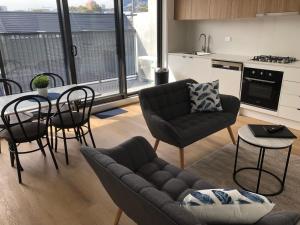 メルボルンにあるQ Squared Serviced Apartmentsのソファとテーブルと椅子のあるリビングルーム