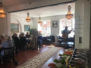 a group of people sitting in a restaurant with a man playing guitar at HotelPandekagehuset B&B in Nykøbing Sjælland