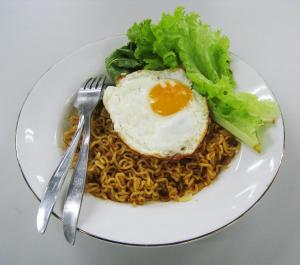 a plate of food with an egg on top of noodles at West Surabaya Homey in Surabaya