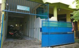 a motorcycle parked in front of a building with a blue gate at West Surabaya Homey in Surabaya