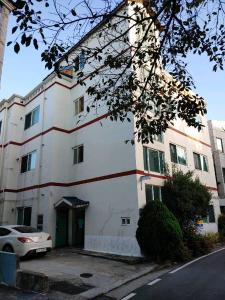 un edificio blanco con un coche aparcado delante de él en Gimhae Guest House en Gimhae