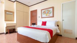 1 dormitorio con 1 cama blanca grande con almohadas rojas en RedDoorz @ Downtown Tacloban, en Tacloban