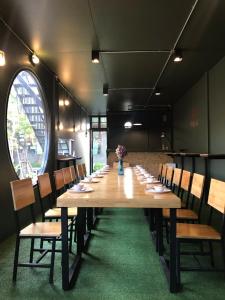 een lange houten tafel in een kamer met houten stoelen bij Paksina Hotel in Narathiwat