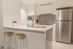 a kitchen with a stainless steel refrigerator and stools at Highlife Luxury*Carpark*Wifi*Pool*Gym*Netflix in Brisbane