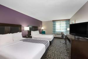 a hotel room with two beds and a flat screen tv at La Quinta by Wyndham Blue Springs in Blue Springs