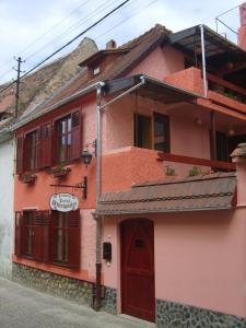 a pink building with red doors on a street at Pensiunea Podul Minciunilor in Sibiu